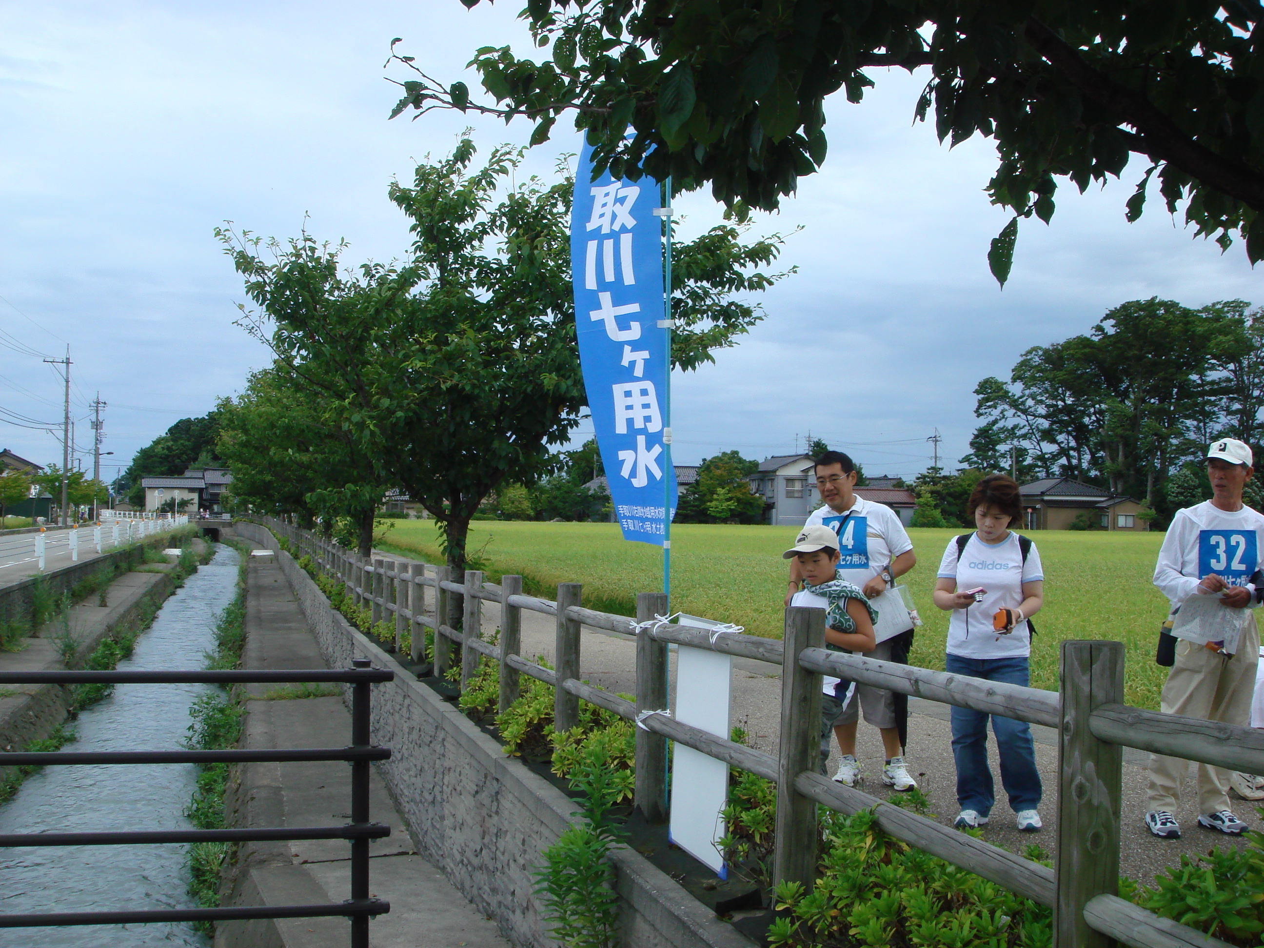 写真  郷用水沿いでクイズに悩む参加者